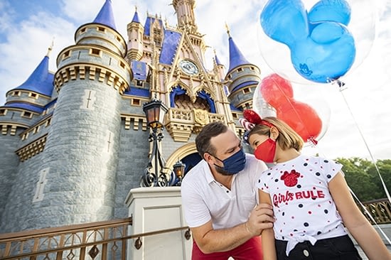 A father & daughter wearing masks in front of Cinderella Castle at Disney's Magic Kingdom Theme Park