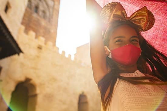 A girl wearing a mask and Minnie mouse ears at Epcot.